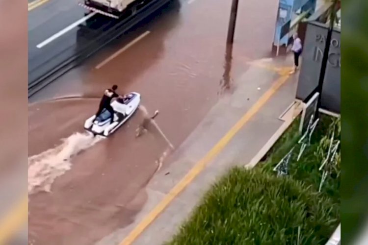 Homem usa jet-ski para andar na rua em dia de chuva forte em Goiânia